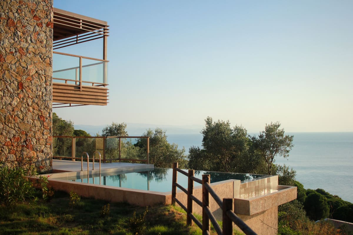 A modern outdoor pool area with a stone wall and a wooden deck.