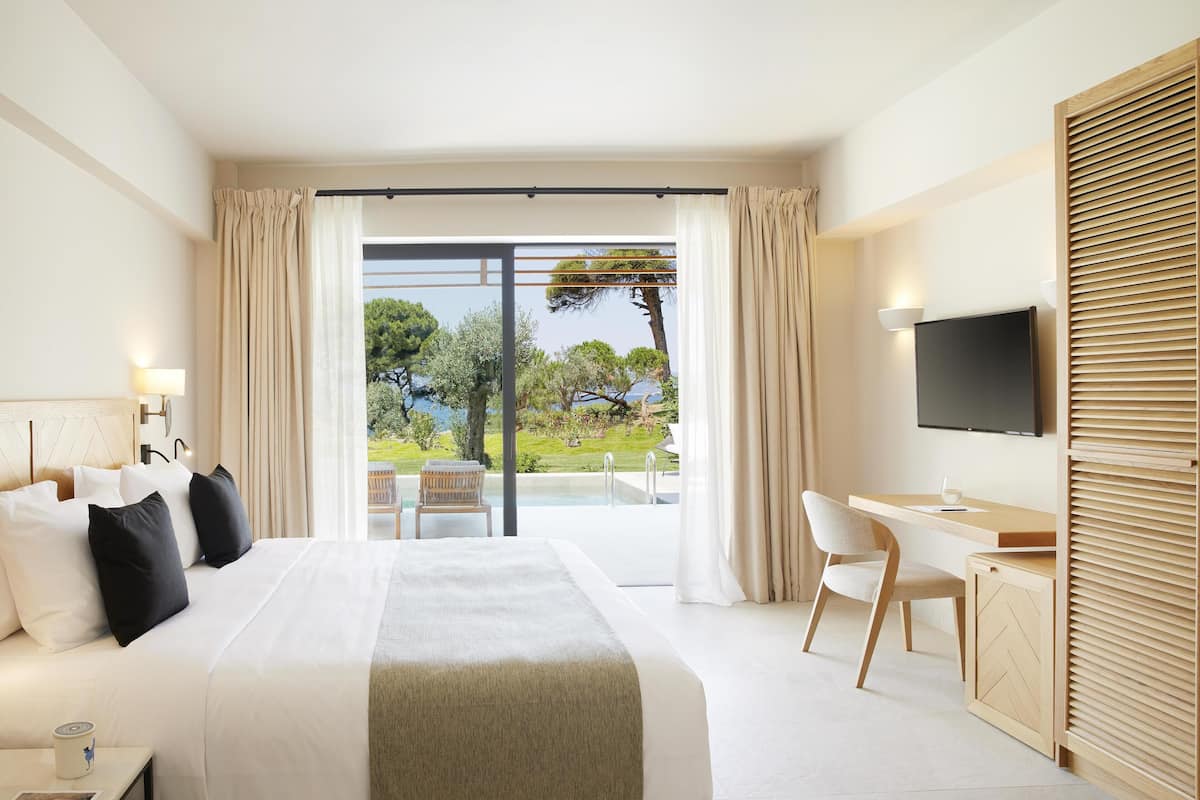 A modern hotel room with a large bed, a desk, and a TV.