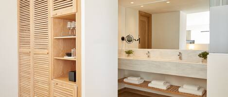 A modern bathroom with a wooden vanity, a large mirror, and neatly folded towels.