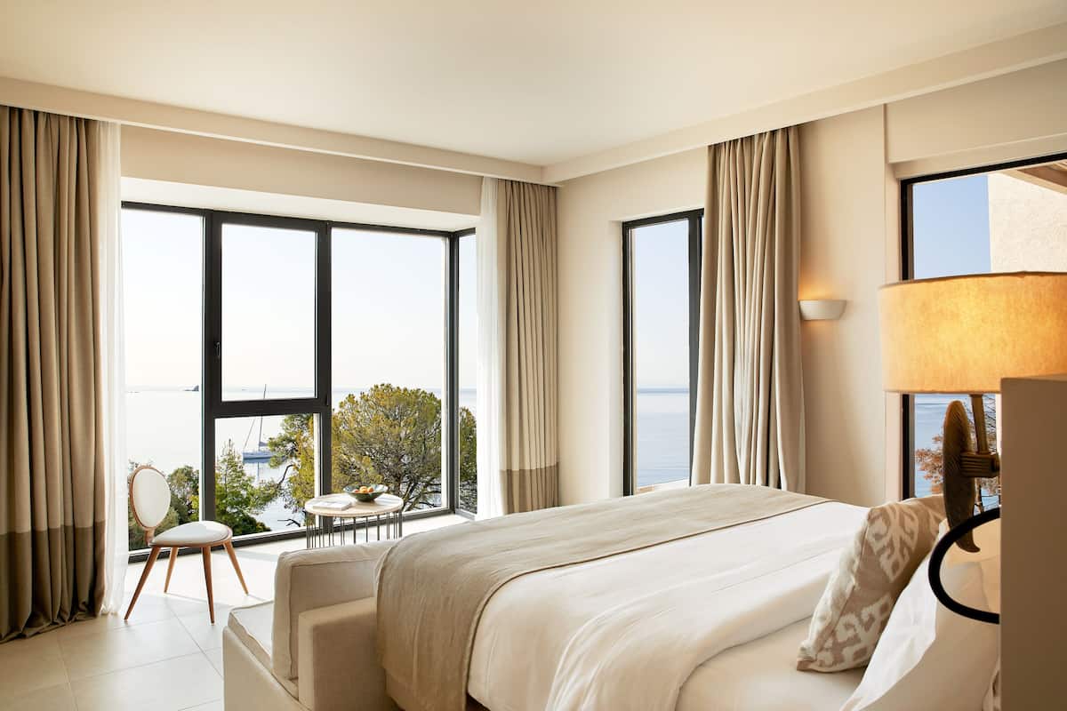 A hotel room with a large bed, a desk, and a view of the sea.