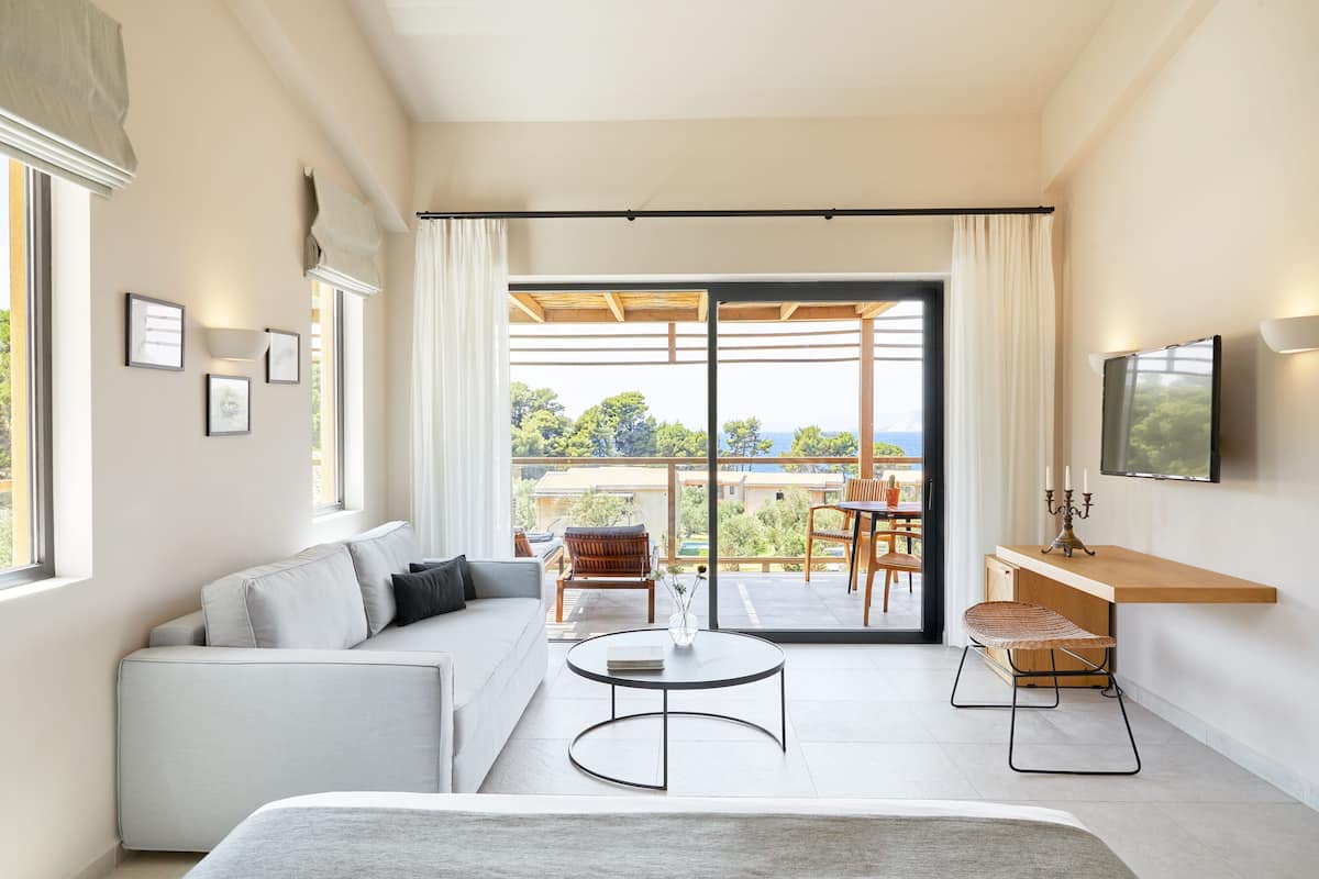A modern living room with a sofa, coffee table, and a view of the outdoors through large sliding doors.