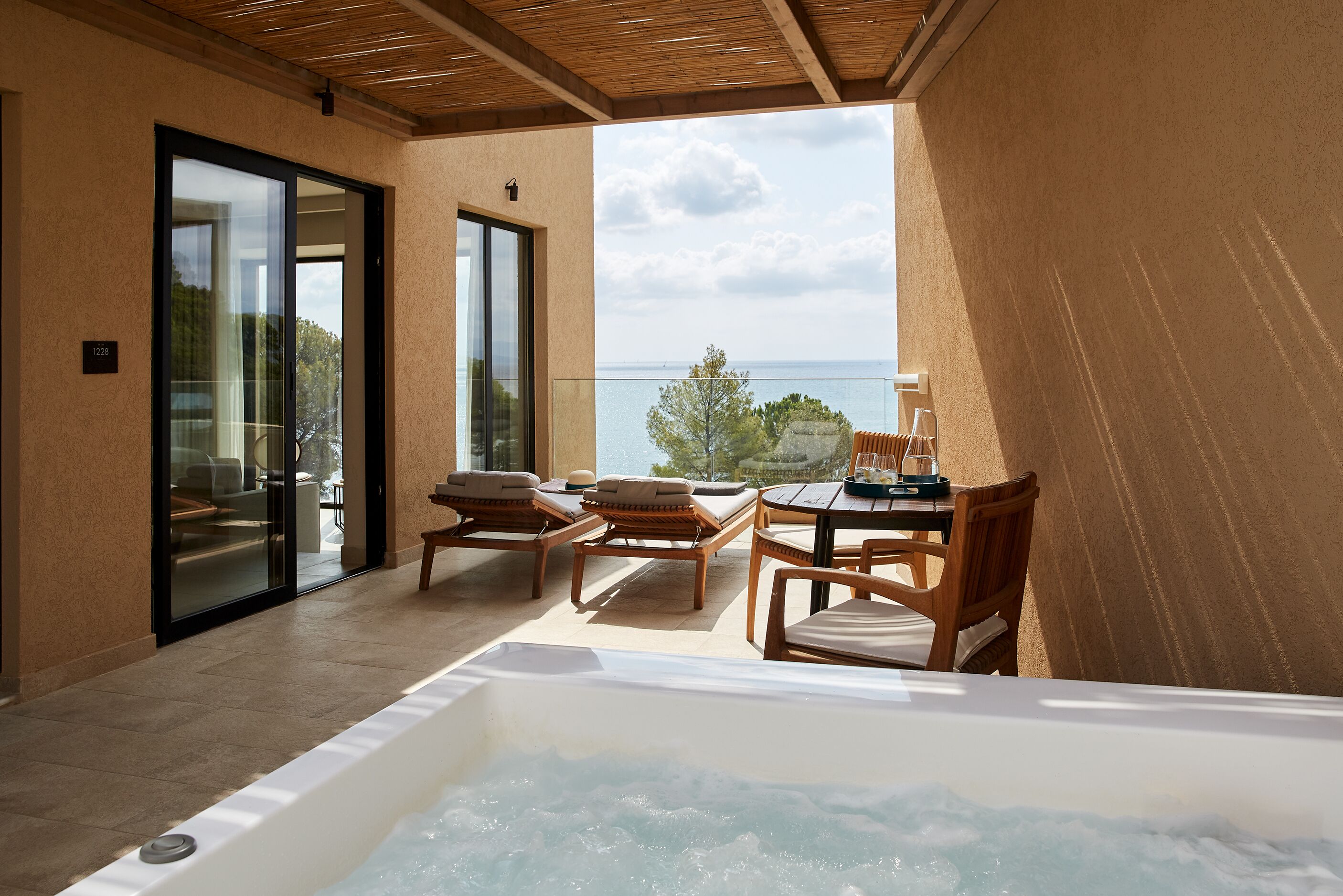 Un balcon doté d’un jacuzzi, de meubles en osier et offrant une vue sur la mer.