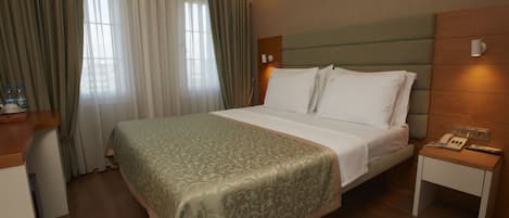 Una habitación de hotel con cama, mesita de noche y cortinas.