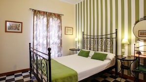 Un dormitorio con cama, piso a cuadros, pared a rayas y ventana con cortinas.