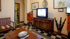 Una sala de estar con televisor, muebles de madera y obras de arte en las paredes.