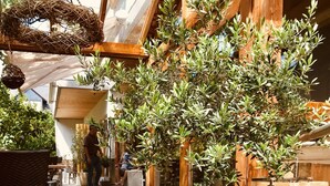 An outdoor seating area with wicker furniture, potted plants, and a display of purple flowers. - Hotel Weingut Dehren (Ellenz-Poltersdorf)