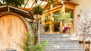 A wooden building with a large door, stone steps, and a sign with greetings. - Hotel Weingut Dehren (Ellenz-Poltersdorf)