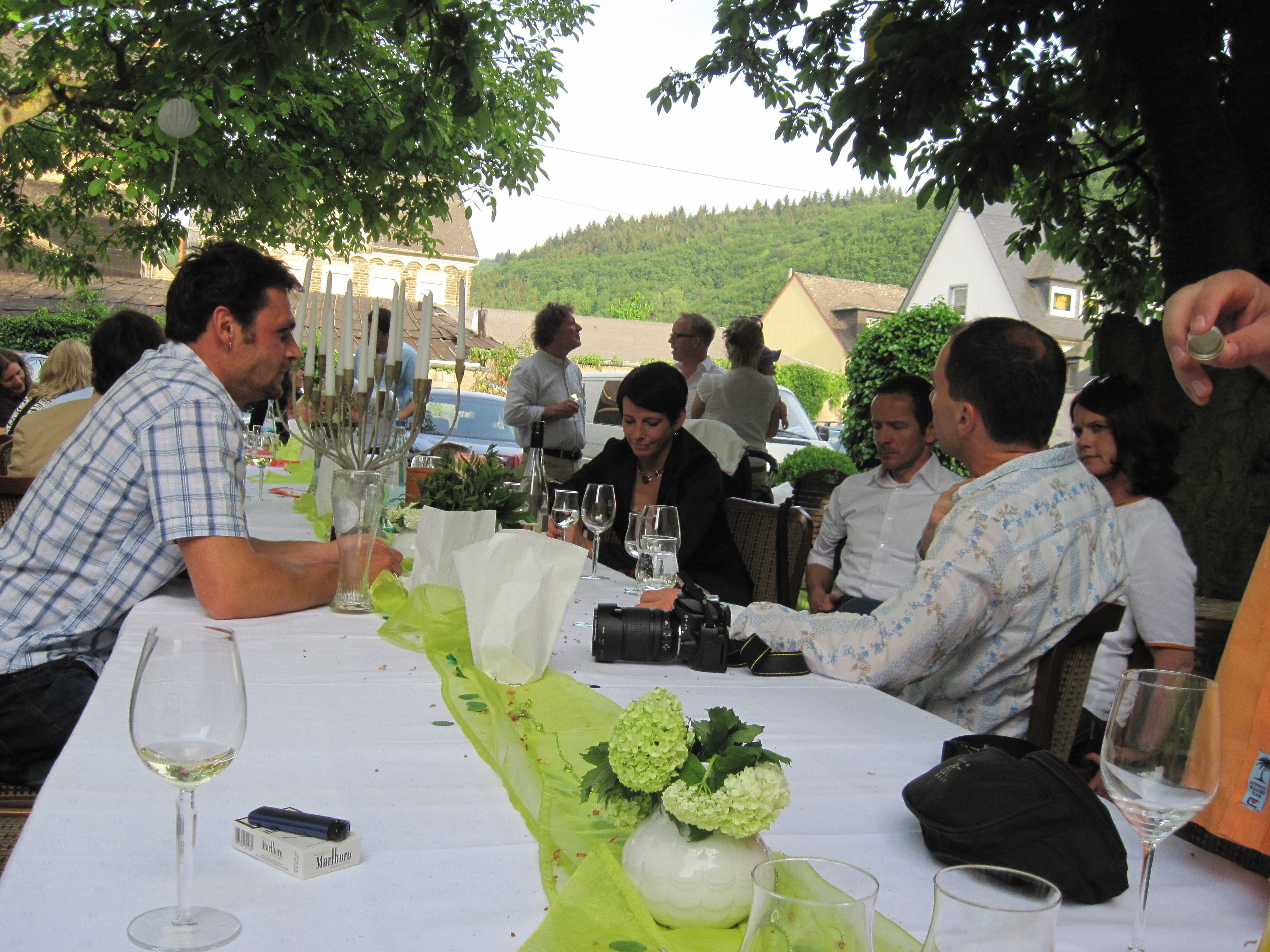 A dining table with a white tablecloth, a vase with flowers, and several wine glasses.