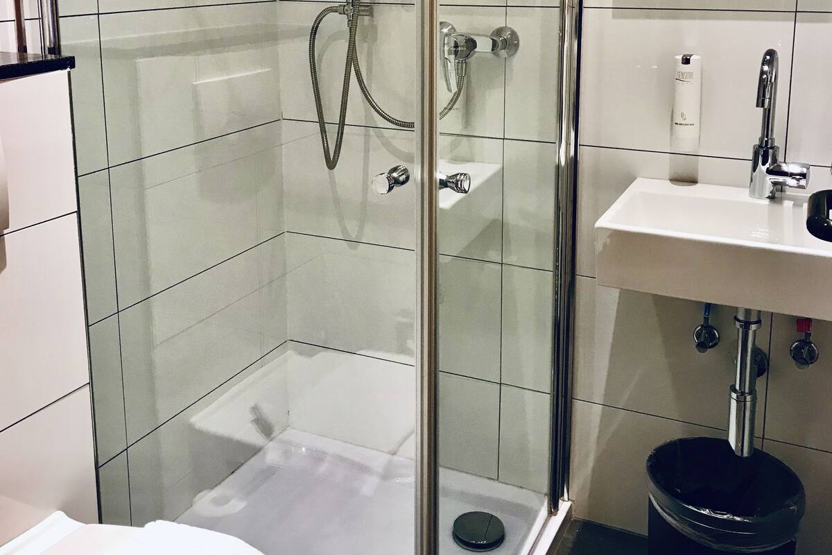 A modern bathroom with a glass-enclosed shower, a white sink, and a toilet.
