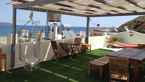 Un patio al aire libre con pérgola, mobiliario y vista al mar.