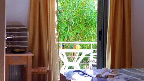 A room with a bed, a small table with colorful mugs, and a view of greenery outside. - Lion-Suites (Apokoronas)