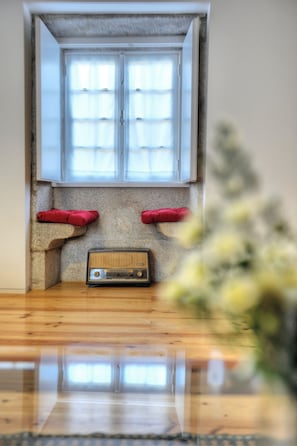 Ein Zimmer mit Fenster, einem Radio und zwei roten Kissen an einer Steinwand.