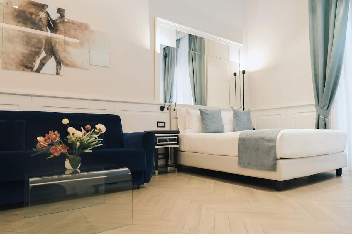 Un soggiorno moderno con un divano blu, un divano bianco e un tavolino in vetro con fiori.