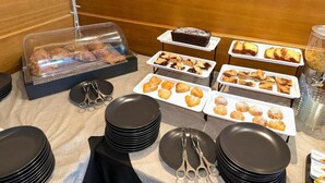 Ein Buffet mit verschiedenen Backwaren und Desserts, darunter ein Schokoladenkuchen, auf weißen Tabletts angerichtet.