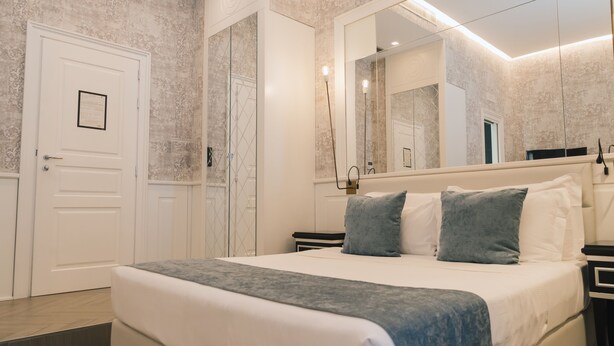 Ein Schlafzimmer mit einem großen Bett, einem Spiegel, einer Tür und einem Nachttisch.