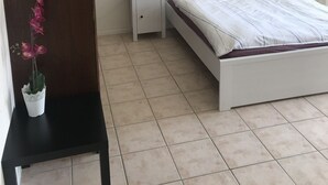 Ein Schlafzimmer mit Bett, Nachttisch, Kommode und einem Wandbild.