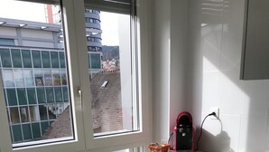 Eine moderne Küche mit einem eingebauten Geschirrspüler, einer roten Kaffeemaschine und einem Fenster mit Blick auf eine Stadtlandschaft.