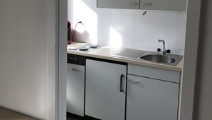 Eine kleine Küche mit weißen Schränken, einer Spüle und einem Geschirrspüler.