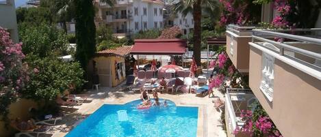 Una piscina al aire libre, sombrillas, sillones reclinables de piscina