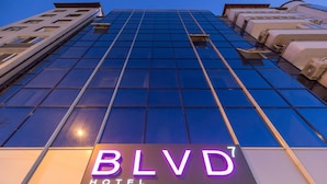 Exterior del HOTEL BLVD7, con fachada moderna de vidrio y señalización iluminada.