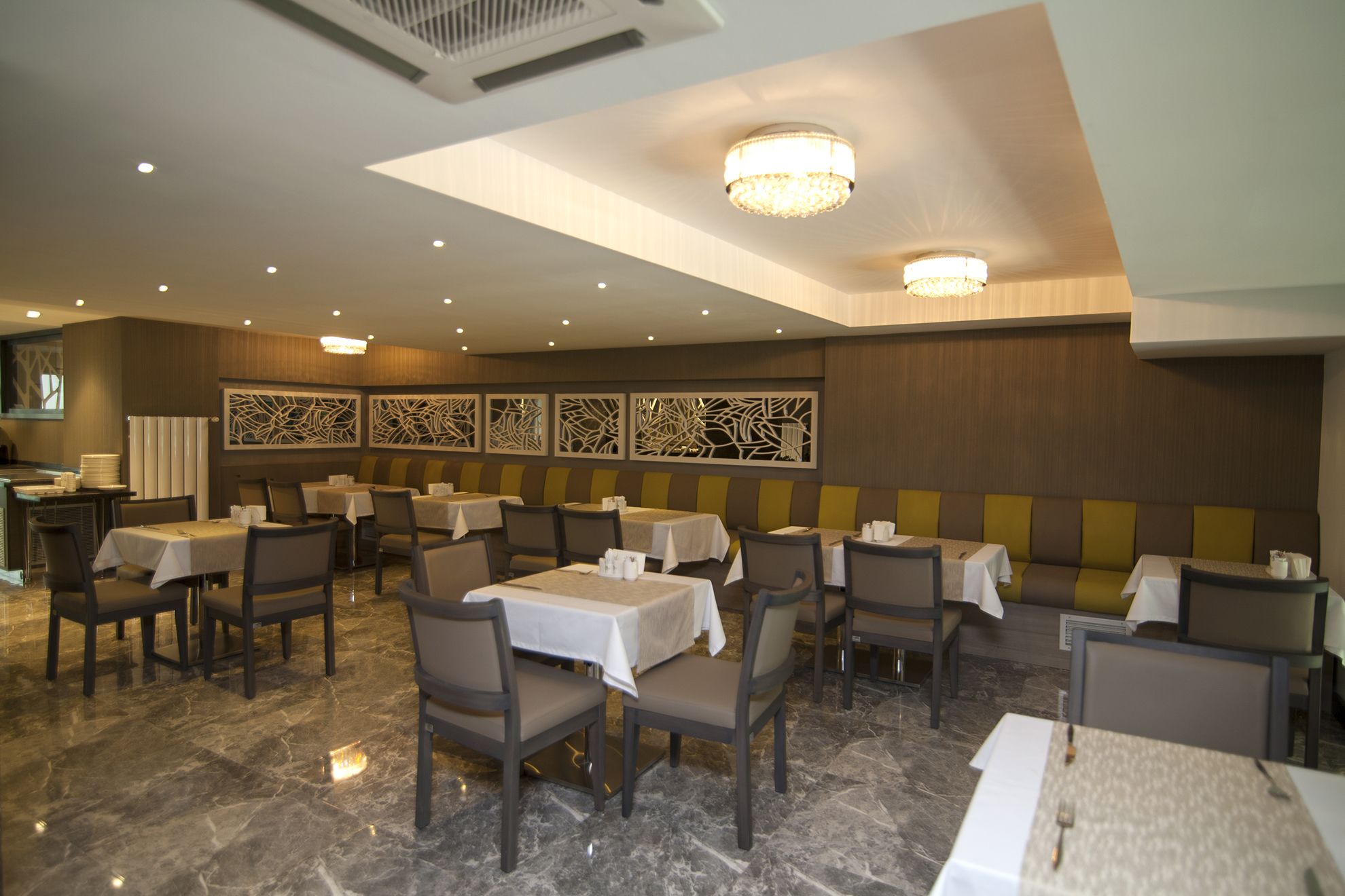 A restaurant with multiple tables and booths, marble flooring, and decorative wall panels.