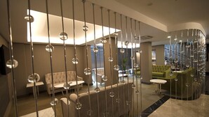 A modern interior with a central seating area, a staircase, and a glass partition with hanging spherical lights. - Yeni Bahar Otel (Ankara)