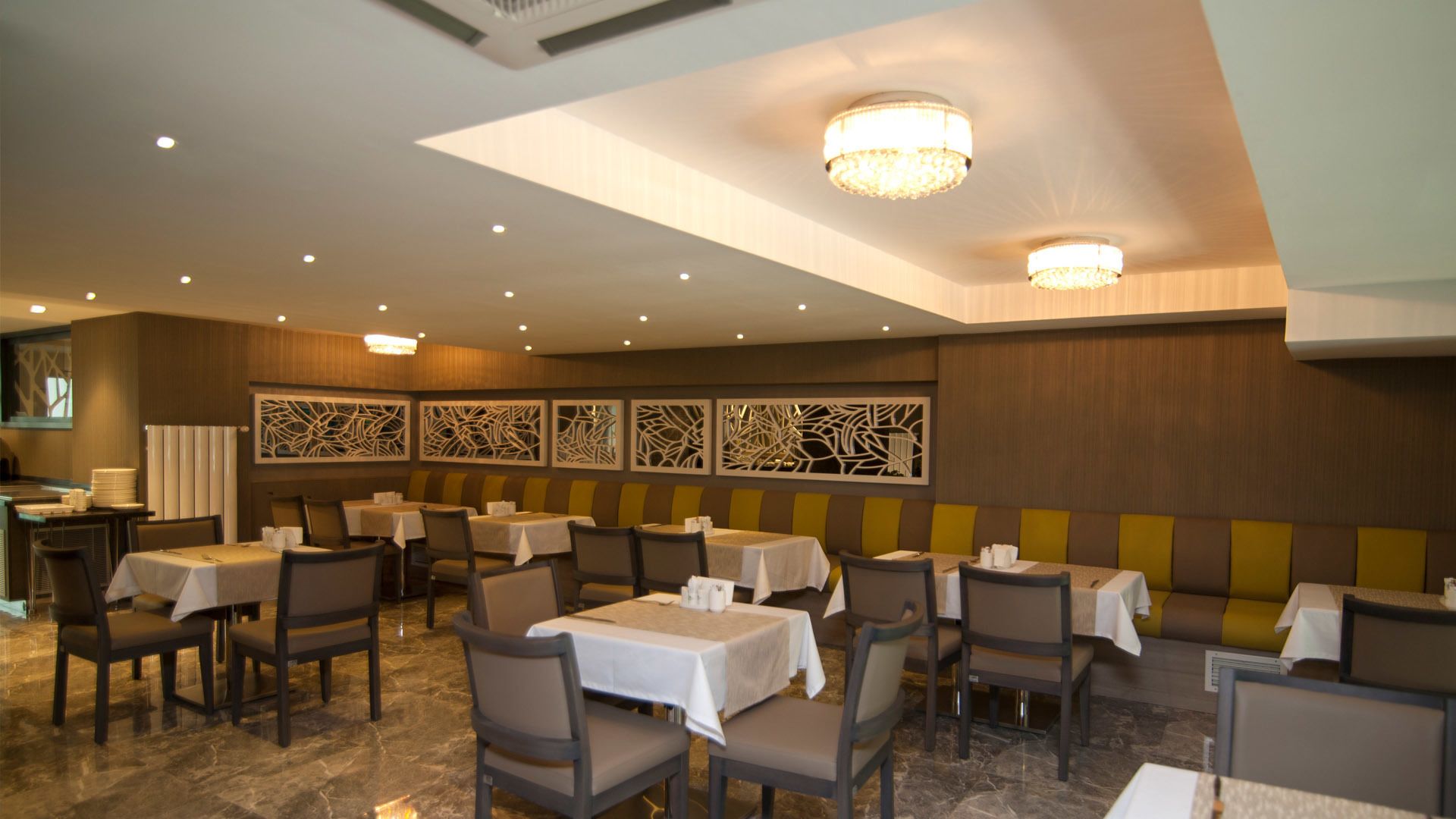 A restaurant with multiple tables and booths, recessed lighting, and decorative wall panels.