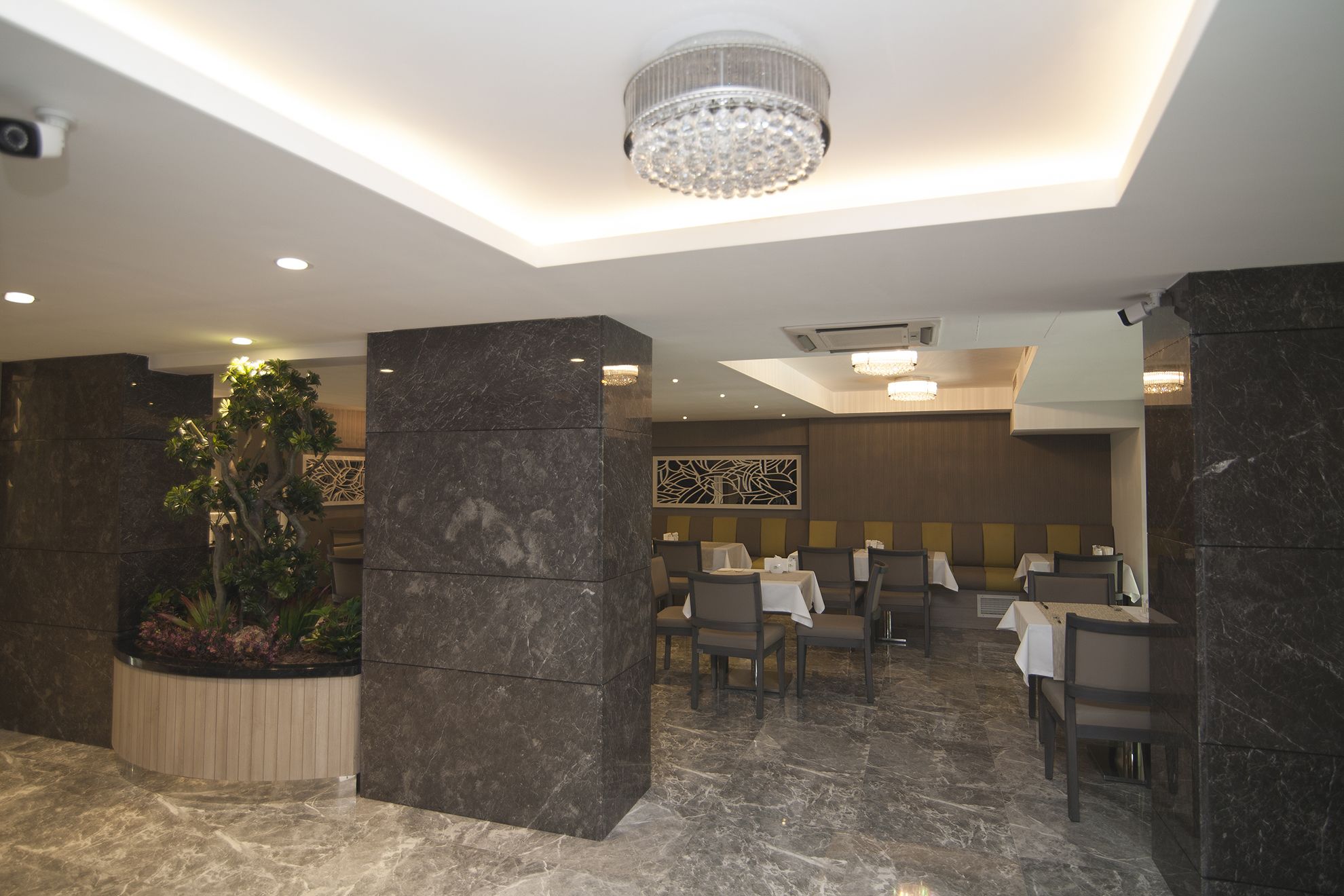 Un restaurante moderno con suelos de mármol, pilares de piedra oscura y una araña.