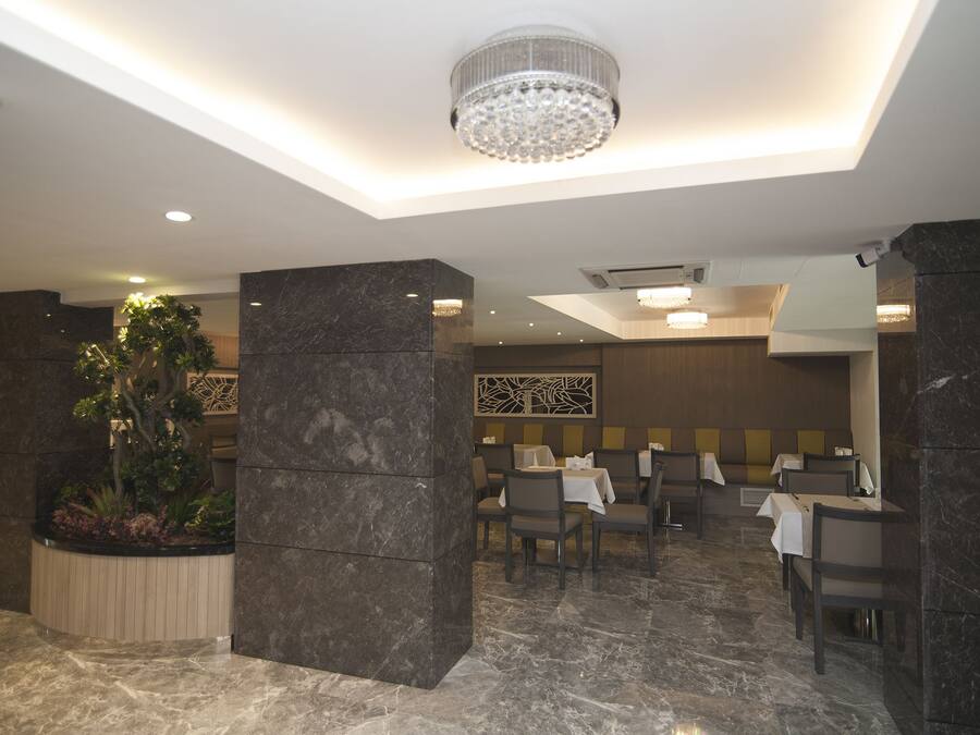 Un restaurante moderno con suelos de mármol, pilares de piedra oscura y una araña.