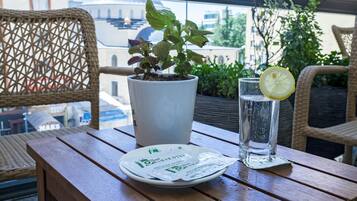 Una mesa de madera con una planta en maceta, un vaso de agua y un plato con una rodaja de limón.