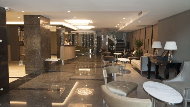 A modern lobby with a reception desk, seating area, and a staircase leading to upper floors. - Yeni Bahar Otel (Ankara)