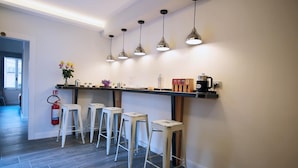 A modern kitchen with bar stools, pendant lights, and a coffee station. - Trevi Contemporary Suite (Rome)