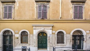 A building with a green door, arched windows, and a yellow facade. - Trevi Contemporary Suite (Rome)