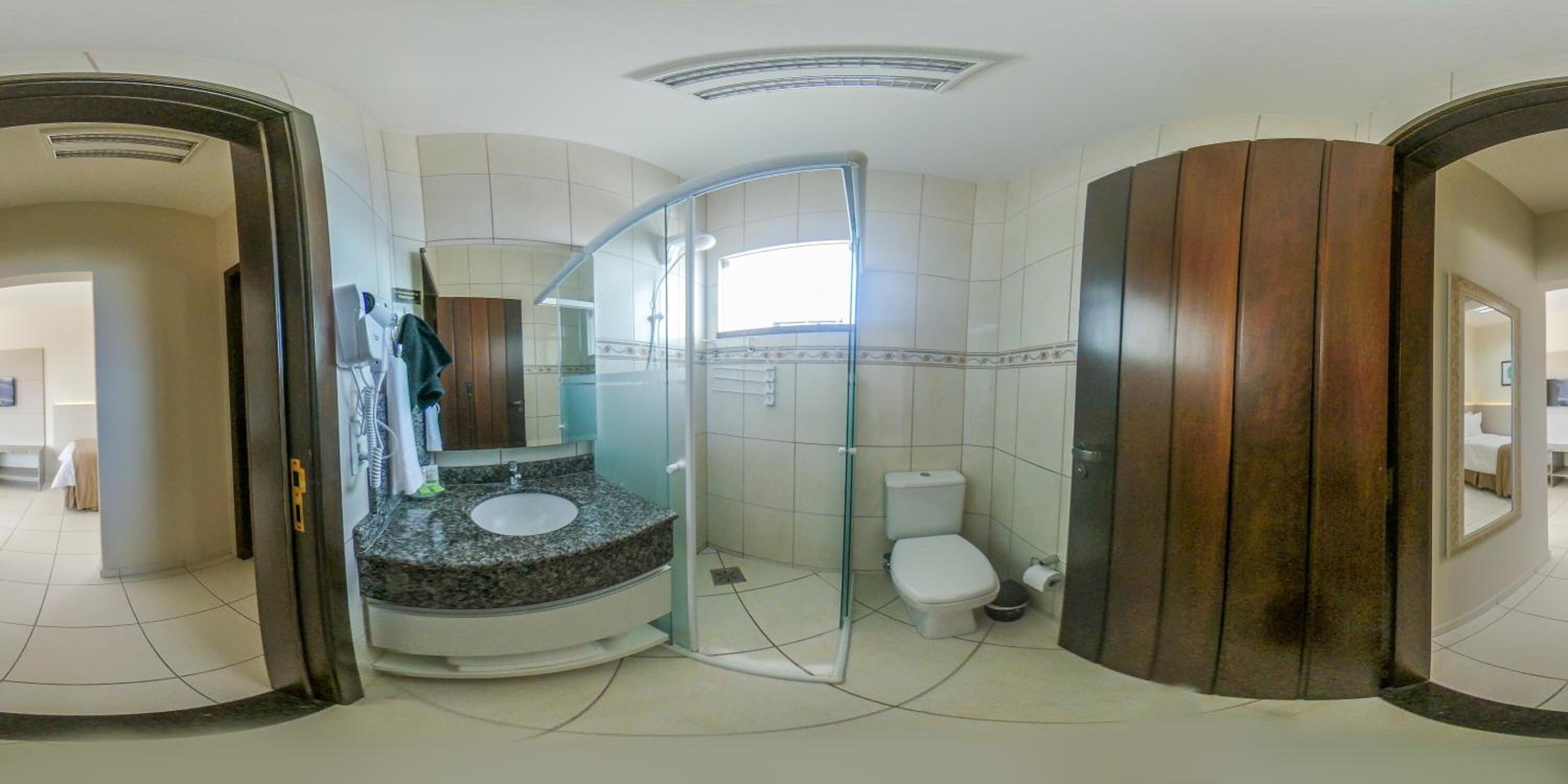 A modern bathroom with a curved glass shower enclosure, a granite countertop sink, and a white toilet.