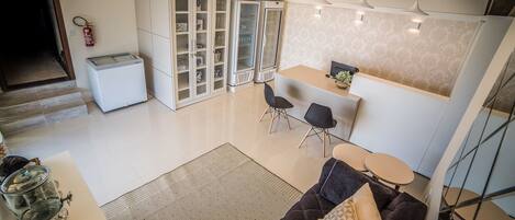A modern kitchen with a refrigerator, cabinets, and a dining area with chairs and a table.