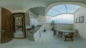 A compact kitchen with a microwave, sink, and a small dining area with stools. - Pousada Doluar (Penha)
