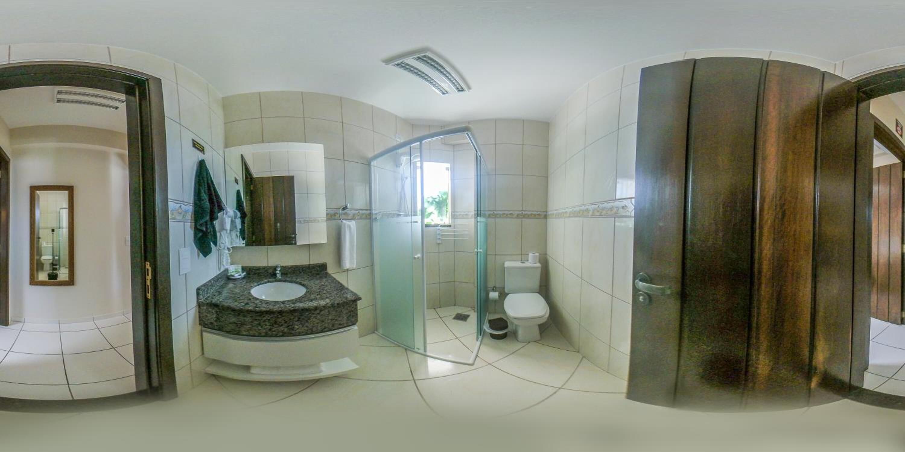 Un baño moderno con lavamanos de granito, cabina de ducha de vidrio y un inodoro.