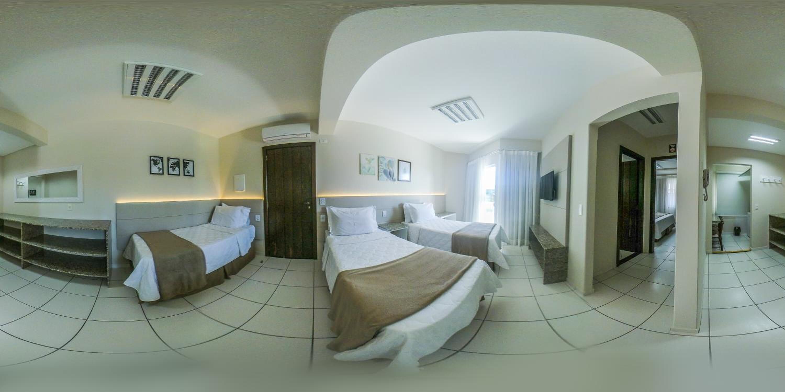 Une chambre d’hôtel avec trois lits, une télévision et une grande porte en arc donnant sur une autre pièce.