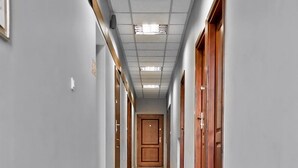 A long, narrow hallway with a polished floor, grey walls, and wooden doors on both sides. - Smart Rooms for Rent (Kraków)