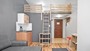A compact room with a bunk bed, kitchenette, and a small seating area. - Smart Rooms for Rent (Kraków)