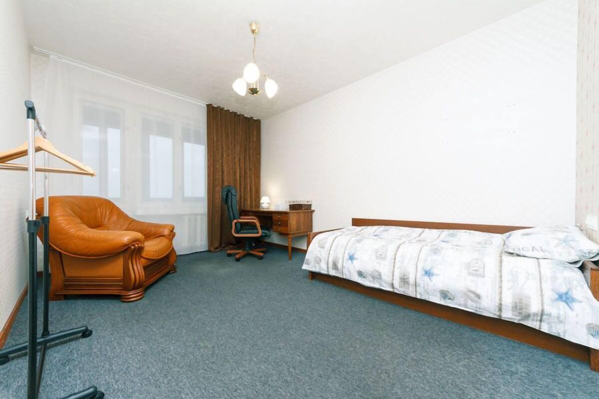 Una habitación de hotel con una cama individual, un escritorio, una silla y una lámpara colgante.