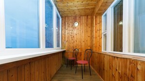 A narrow corridor with wooden walls and large windows, leading to a seating area with two chairs. - Dikat Hostel (Kyiv)