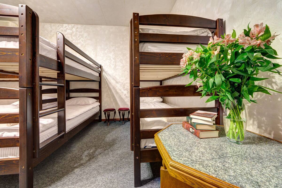 Habitación con literas, una mesita pequeña y un jarrón con flores.