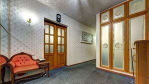A room with a wooden door, a red sofa, a small table, and a cabinet. - Dikat Hostel (Kyiv)