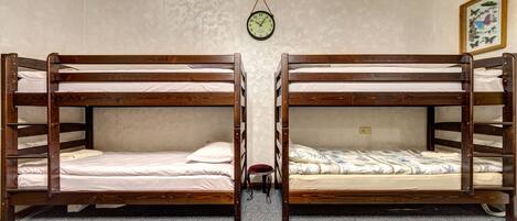 Una habitación con dos literas, un taburete pequeño, un reloj y un cuadro en la pared.