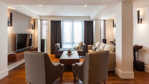 Een moderne woonkamer met een flatscreen televisie, twee fauteuils, een bank en een salontafel.