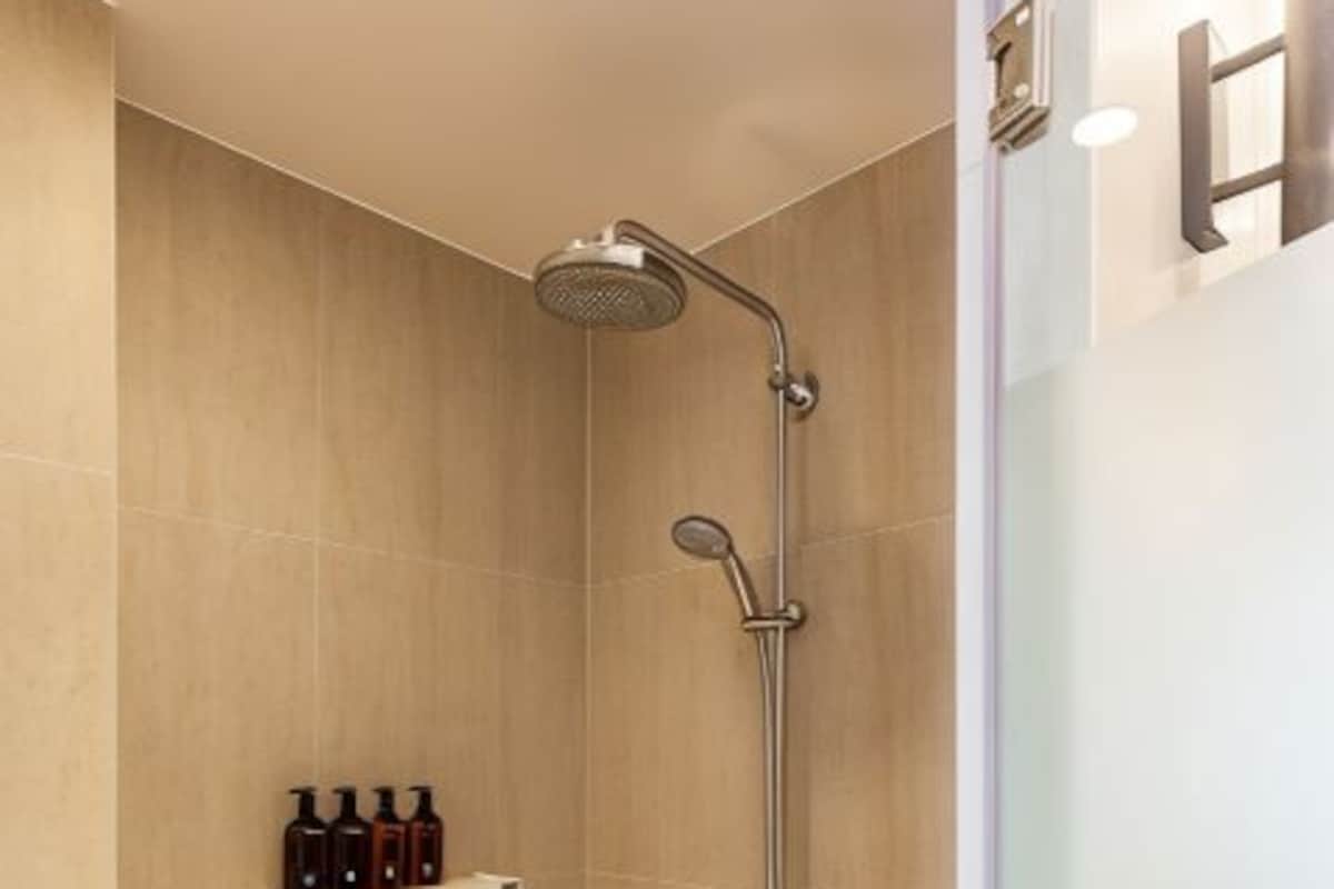 A modern shower with a handheld showerhead and a wall-mounted faucet.