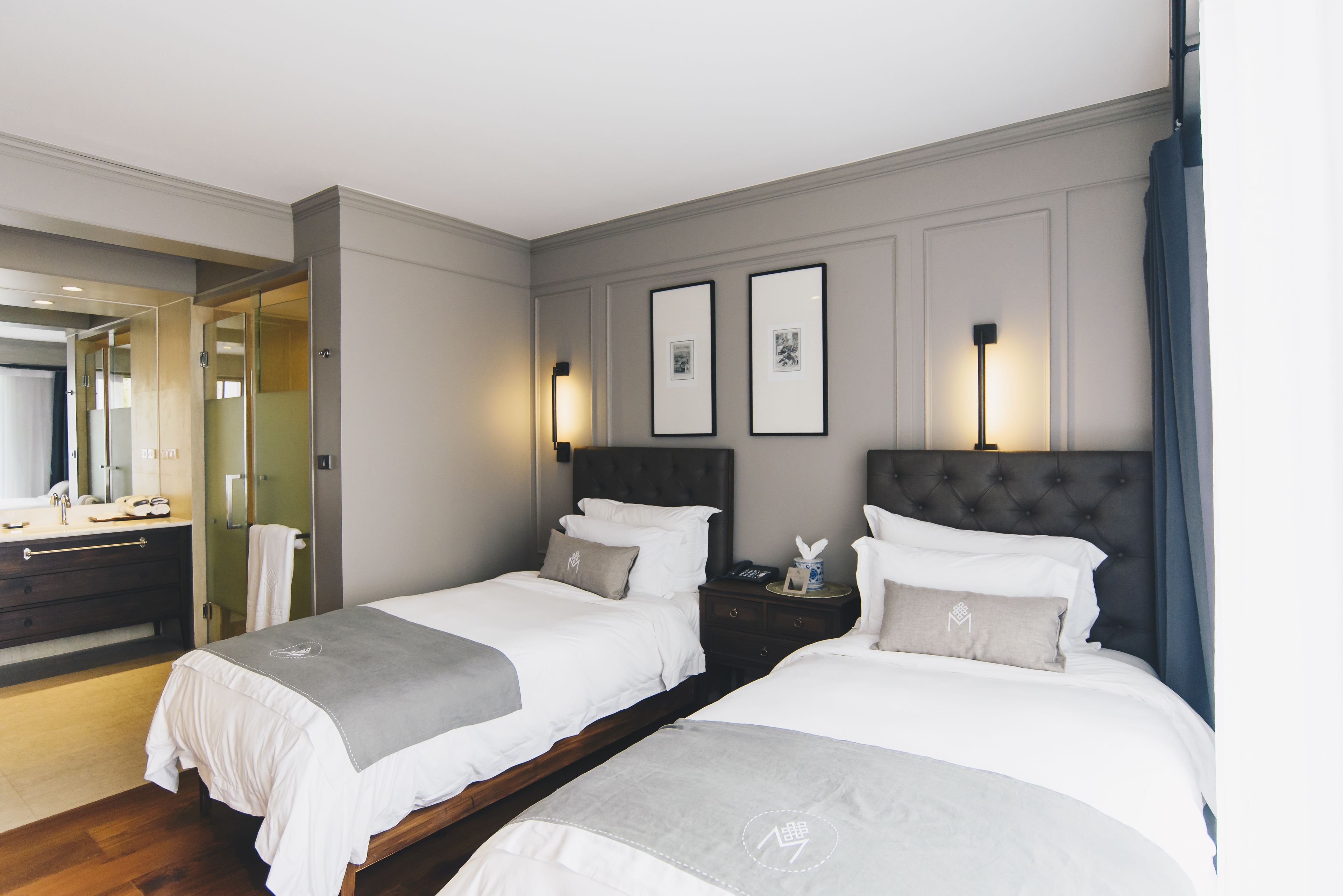 A hotel room with two beds, a bathroom, and a mirror.