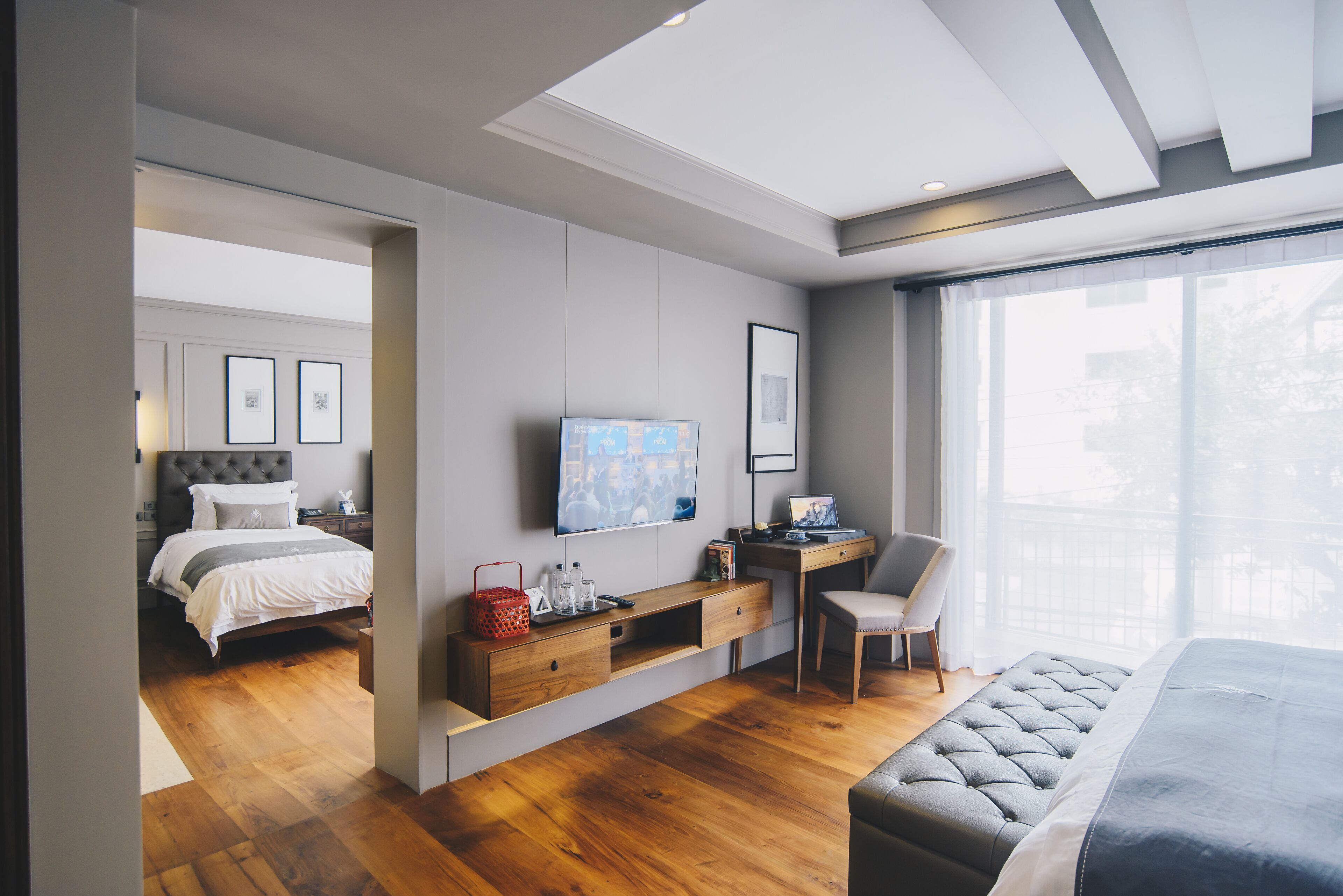 A modern bedroom with a bed, a desk, a chair, and a TV.