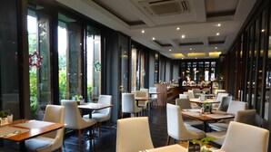 Een modern restaurant met een lange toonbank, meerdere tafels en stoelen.